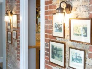 una pared de ladrillo con cuadros enmarcados en ella en The White Horse Inn, en Pulborough