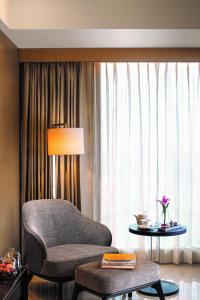 a living room with a chair and a table and a window at Jaypee Siddharth in New Delhi