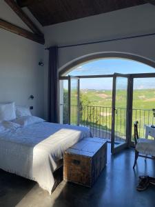 een slaapkamer met een bed en een groot raam bij Tenuta Le More in Calosso