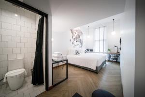 拉廊Blu Monkey Hub & Hotel Ranong的一间带床和浴室的白色卧室