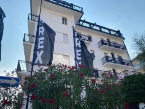 un edificio con banderas y flores delante de él en Hotel Rex, en Lido di Savio