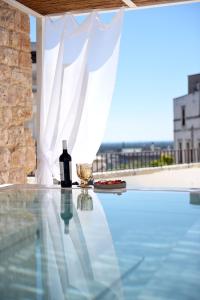 a bottle of wine and a glass on a table on a swimming pool at Arya Nobile Dimora in Carovigno