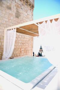 a swimming pool with blue water and white curtains at Arya Nobile Dimora in Carovigno