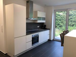 a kitchen with white cabinets and a sink and a stove at Gästehaus Witteborg in Paderborn