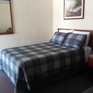 a bedroom with a bed with a plaid blanket at Windsor Crossroads Motel in Windsor