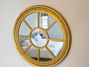 a gold mirror on a wall with a bed at Woodberry Inn in Bridgnorth
