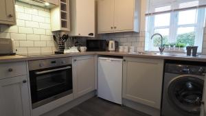a kitchen with a washer and a sink and a dishwasher at Woodlands View in Halesworth