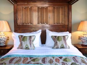 a bed with a wooden headboard and two lamps at Woolmarket House in Chipping Campden