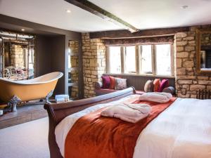 a bedroom with a large bed and a bath tub at Woolmarket House in Chipping Campden