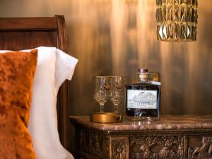 a bottle of whiskey on a table next to a bed at Woolmarket House in Chipping Campden
