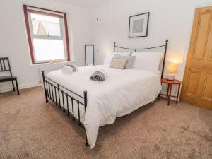 a bedroom with a large bed with white sheets and a window at Cheviot Way Cottage in Wooler
