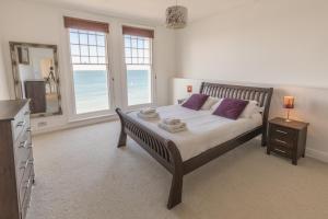 a bedroom with a bed with purple pillows and a mirror at Water's Edge Apartment in Totland