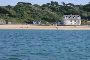 a view of a beach with a house and the water at Water's Edge Apartment in Totland