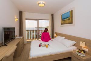 a woman sitting on a bed in a hotel room at Poseidon The Beach Hotel in Budva