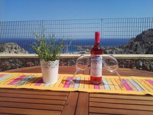 a bottle of wine and two glasses on a table at Bouganville apartment Stegna in Archangelos