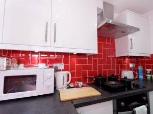 a kitchen with a white microwave and red tiles at Berkley Studio in Leeds