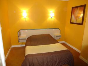 Hôtel La Champagne Ardenne Cabourg في كابورغ: غرفة نوم مع سرير مع مصباحين على الحائط