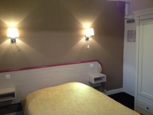 um quarto com uma cama e duas luzes na parede em Hôtel La Champagne Ardenne Cabourg em Cabourg