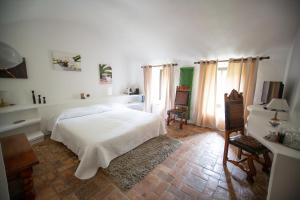 een slaapkamer met een wit bed en twee stoelen bij Châteauzen in Madières