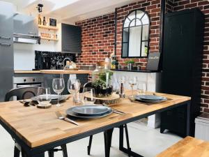 - une table en bois avec des assiettes et des verres dans la cuisine dans l'établissement La Fabrique Cherbourgeoise - Les Loges Normandes, à Cherbourg en Cotentin