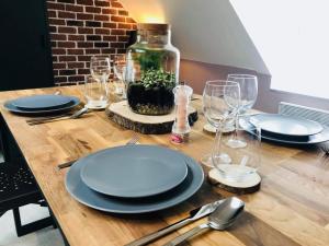 Una mesa de madera con platos y copas de vino encima. en La Fabrique - Les Loges Normandes, en Cherbourg-en-Cotentin