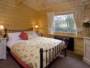 een slaapkamer met een bed in een blokhut bij Cherbridge Lodges - Riverside lodges, short lets (business or holidays) in Oxford