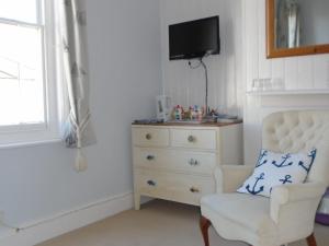 1 dormitorio con vestidor, silla y TV en Cherry End Bed and Breakfast, en Chichester