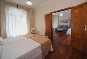a bedroom with a large bed and a living room at Hotel Apartamentos Dabarca in Pontevedra