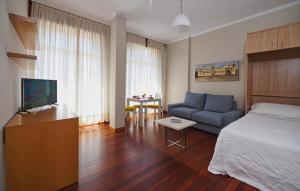 a bedroom with a bed and a couch and a table at Hotel Apartamentos Dabarca in Pontevedra