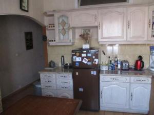 eine Küche mit weißen Schränken und einem schwarzen Kühlschrank in der Unterkunft Chez Brigitte Guesthouse in Nizza