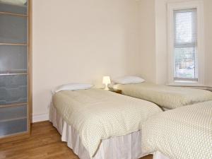 two beds in a room with white walls at Chumleigh Lodge Hotel Ltd. in Hendon