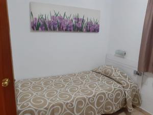 una camera da letto con un letto con fiori viola sul muro di Niza Apartamentos a Mogán