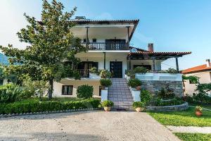 a large house with a staircase in front of it at Pantelidis Rooms in Skala Potamias