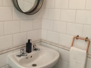 Baño blanco con lavabo y espejo en The Clacks Rustic Abode, en Tillicoultry