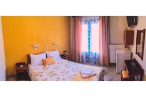 a bedroom with a bed with yellow walls and a window at Pantelidis Rooms in Skala Potamias