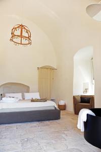 a bedroom with a bed and a chair and a chandelier at Arya Nobile Dimora in Carovigno