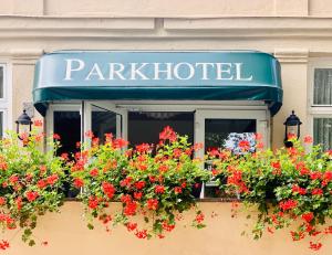 een parkiet hotelbord met rode bloemen in een raam bij Parkhotel Pretzsch in Bad Schmiedeberg