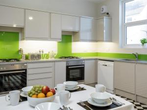 a kitchen with white cabinets and a bowl of fruit on a table at Blue Star House in Portsmouth