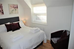 um quarto com uma cama branca e uma cadeira em Coach House em Southampton