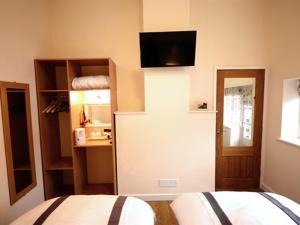 a bedroom with a bed and a room with a television at THE COACHING BARNS in Shrewsbury