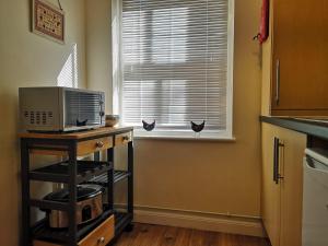 a kitchen with a microwave on a table next to a window at Coastal Escape Deal - 2 Bedroom House at Kent Escapes Short Lets & Serviced Accommodation Kent, Wifi in Deal