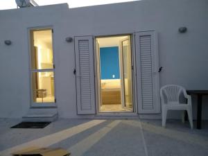 Biały dom z krzesłem i oknem w obiekcie SOUVLIA BEACH w mieście Parasporos