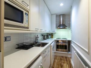 cocina con armarios blancos, fregadero y microondas en Comfortable One Bed in Central, en Londres