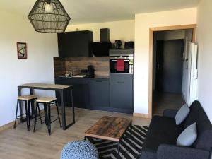 a living room with a couch and a table and a kitchen at La cime des lacs in Gérardmer