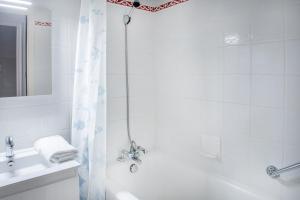 a white bathroom with a shower and a tub and a sink at Hôtel Métropole in Lourdes