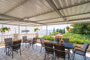 eine Terrasse mit Tischen und Stühlen unter einer Pergola in der Unterkunft Villa Marija Adriatic in Mlini