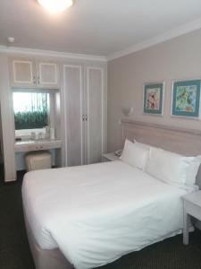 a bedroom with a large white bed and a desk at La Mercy Beach Hotel in La Mercy