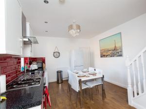 Luxurious Serviced Apartments في ليدز: مطبخ مع طاولة مع كراسي وموقد