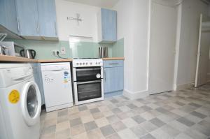 a kitchen with white appliances and blue cabinets at Large Garden flat in the heart of Islington in London