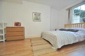 a bedroom with a bed and a dresser and a window at Large Garden flat in the heart of Islington in London